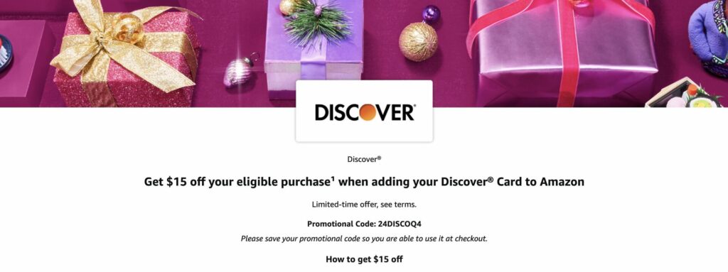 A banner with wrapped holiday gifts, ornaments, and a Discover logo. Text offers $15 off an eligible Amazon purchase when adding a Discover card, with promo code 24DISCOVQ and instructions on how to redeem.