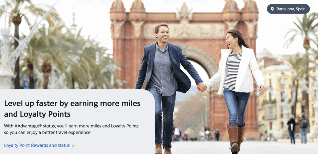 A man and woman holding hands, smiling, and walking near the Arc de Triomf in Barcelona, Spain. The scene is bright and cheerful, with palm trees and people in the background.